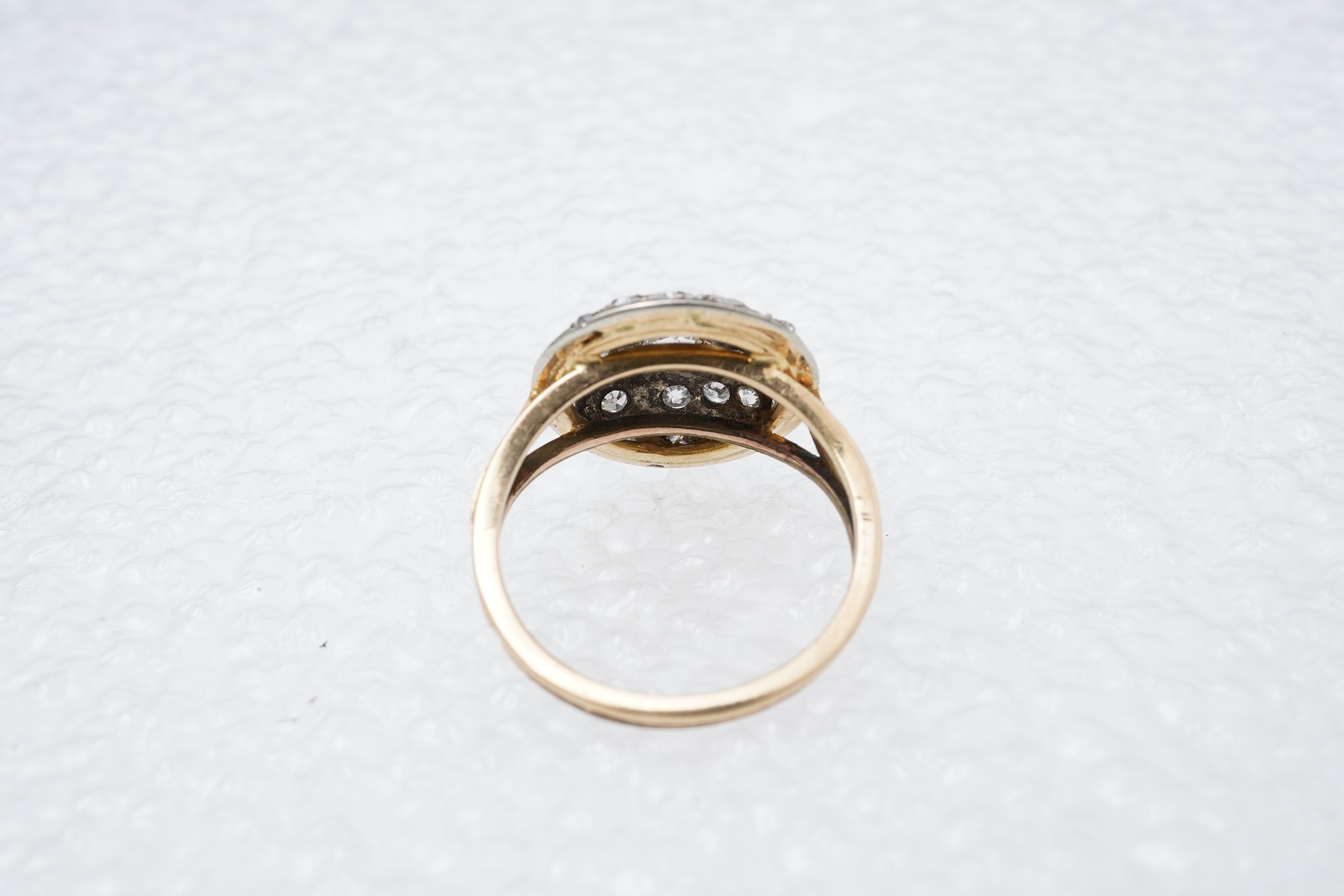 A diamond ring, centring on a circular motif of bombé design, set with geometric arrangements of cushion-shaped, single- and circular-cut diamonds totalling approximately 0.90 carats, to a gold band, size M1/2, indistinc